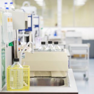 Close-up of laboratory equipment in the newly moved Alderley Analytical lab, featuring precision instruments and several chemical bottles. The setup reflects the state-of-the-art facilities that support the company's business growth and expansion in bioanalytical services. The background reveals a spacious, modern laboratory environment, symbolizing Alderley Analytical's commitment to innovation and high-quality research.