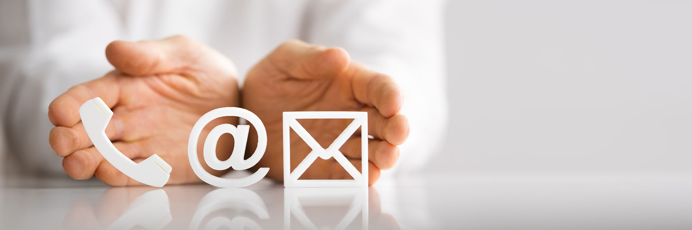 two hands holding telephone icon, email icon, and letter icon